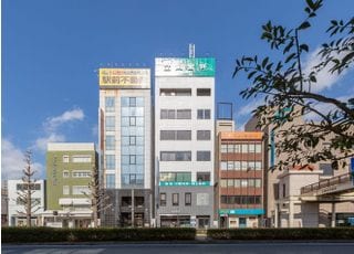 緑の看板が出ているビルです。一階で受付を行ってください。